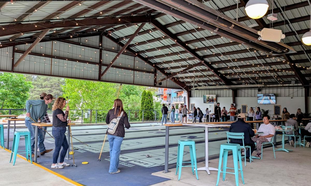 People mingling and playing shuffleboard at Lansing Shuffle.