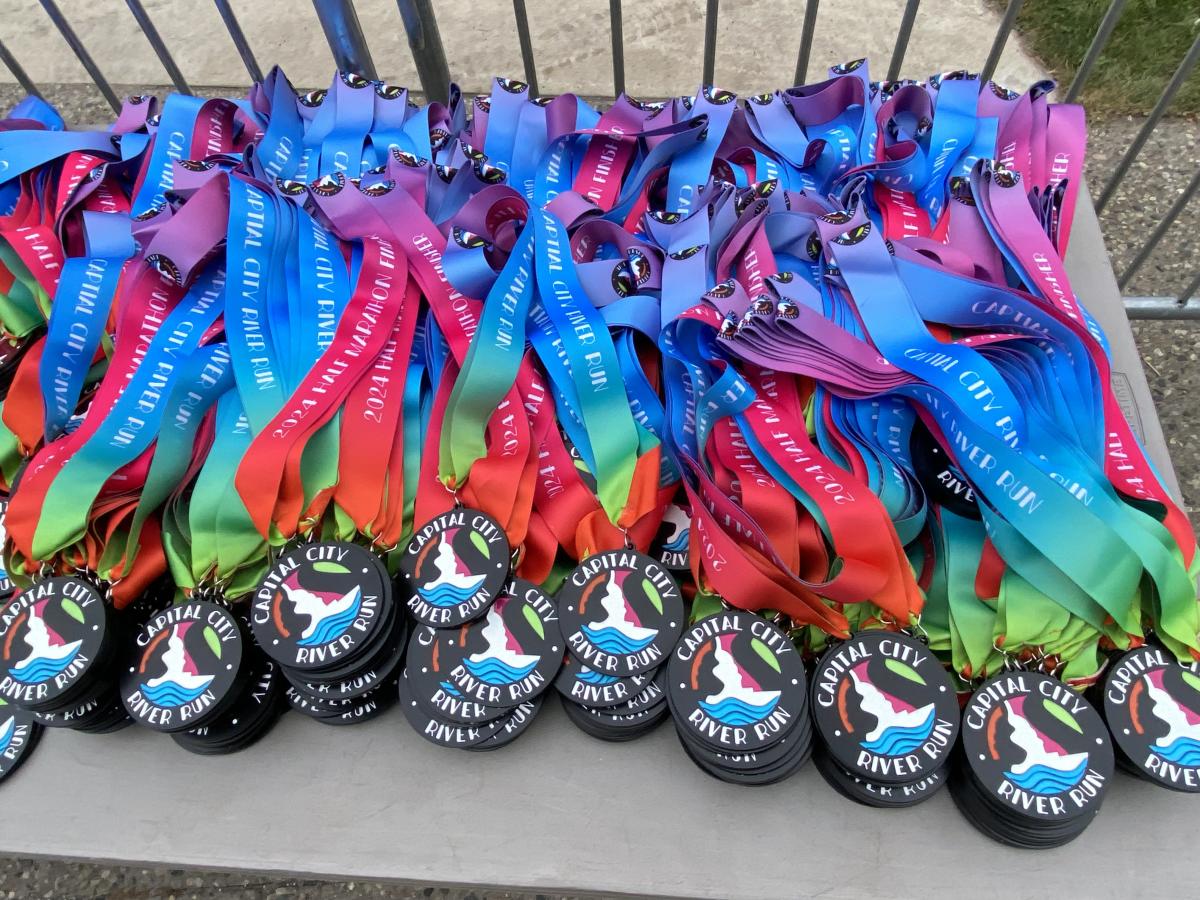 Brightly colored pile of finish medals for the 2024 Capital City River Run.
