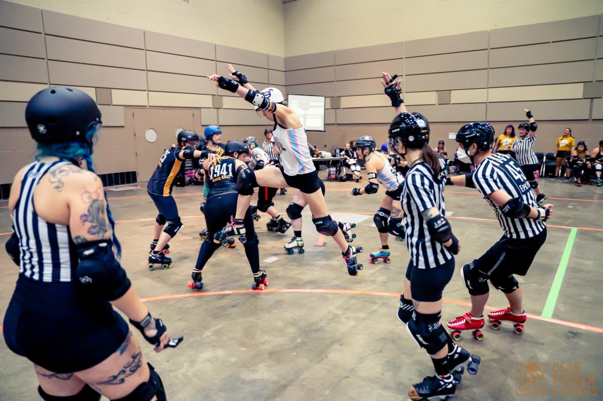 A roller derby participant jumping to avoid competitors at Skate Wars