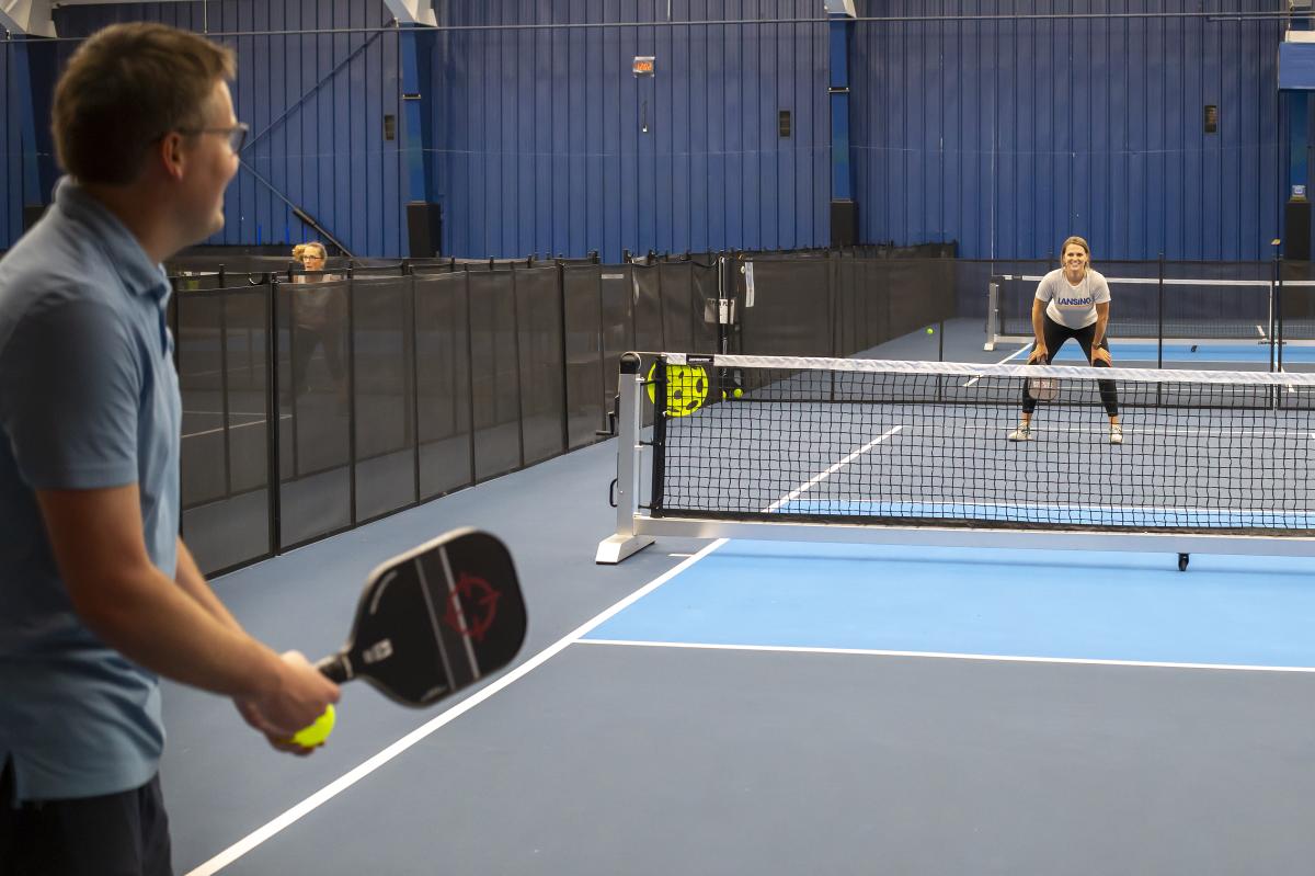 Two people playing pickleball at an indoor court